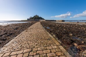 Un sentier pavé de pierres menant à un château historique situé sur une plage rocheuse.