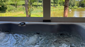 A hot tub with a view of a lake and trees.