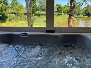A hot tub with a view of a lake and trees.