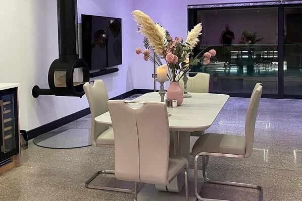 A modern conference room with a white table, beige chairs, and a vase of flowers.