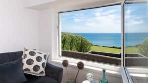 Una habitación con un amplio ventanal que ofrece vistas al mar y al follaje.