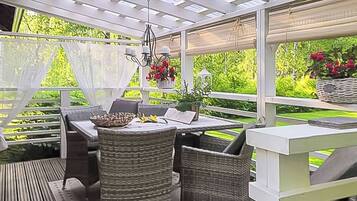 An outdoor patio with wicker furniture, a table, and a hanging light fixture.