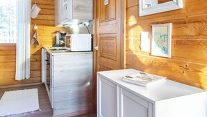 Eine kleine Küche mit Holzwänden, einer weißen Arbeitsplatte und einem Essbereich.