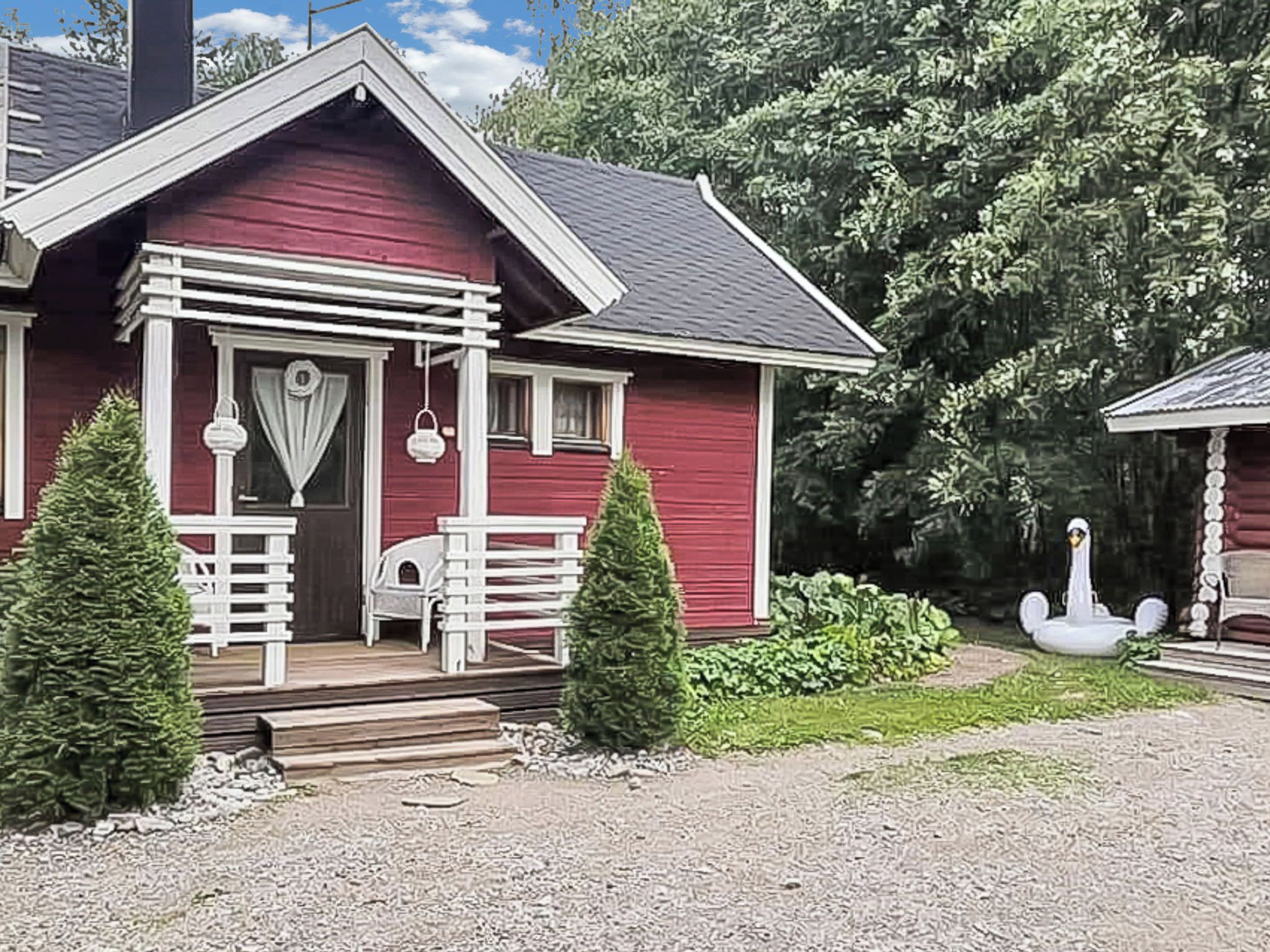A red house with a porch, white railings, and a swan decoration.