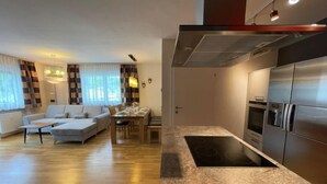 Een moderne keuken met een ingebouwde kookplaat, roestvrijstalen apparatuur en een marmeren aanrecht.