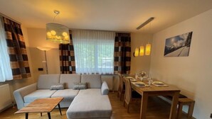 Een moderne woonkamer met een modulaire bank, een houten eettafel en een hanglamp.