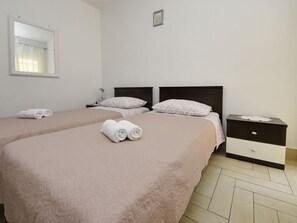 Una habitación de hotel con dos camas, una mesita de noche, un espejo y una ventana con cortinas.