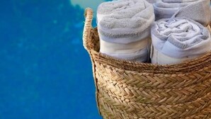 Ein gewebter Korb voller gerollter Handtücher am Pool.