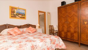 Ein Schlafzimmer mit einem Bett, einem Kleiderschrank, einem Schreibtisch und einem Bild an der Wand.