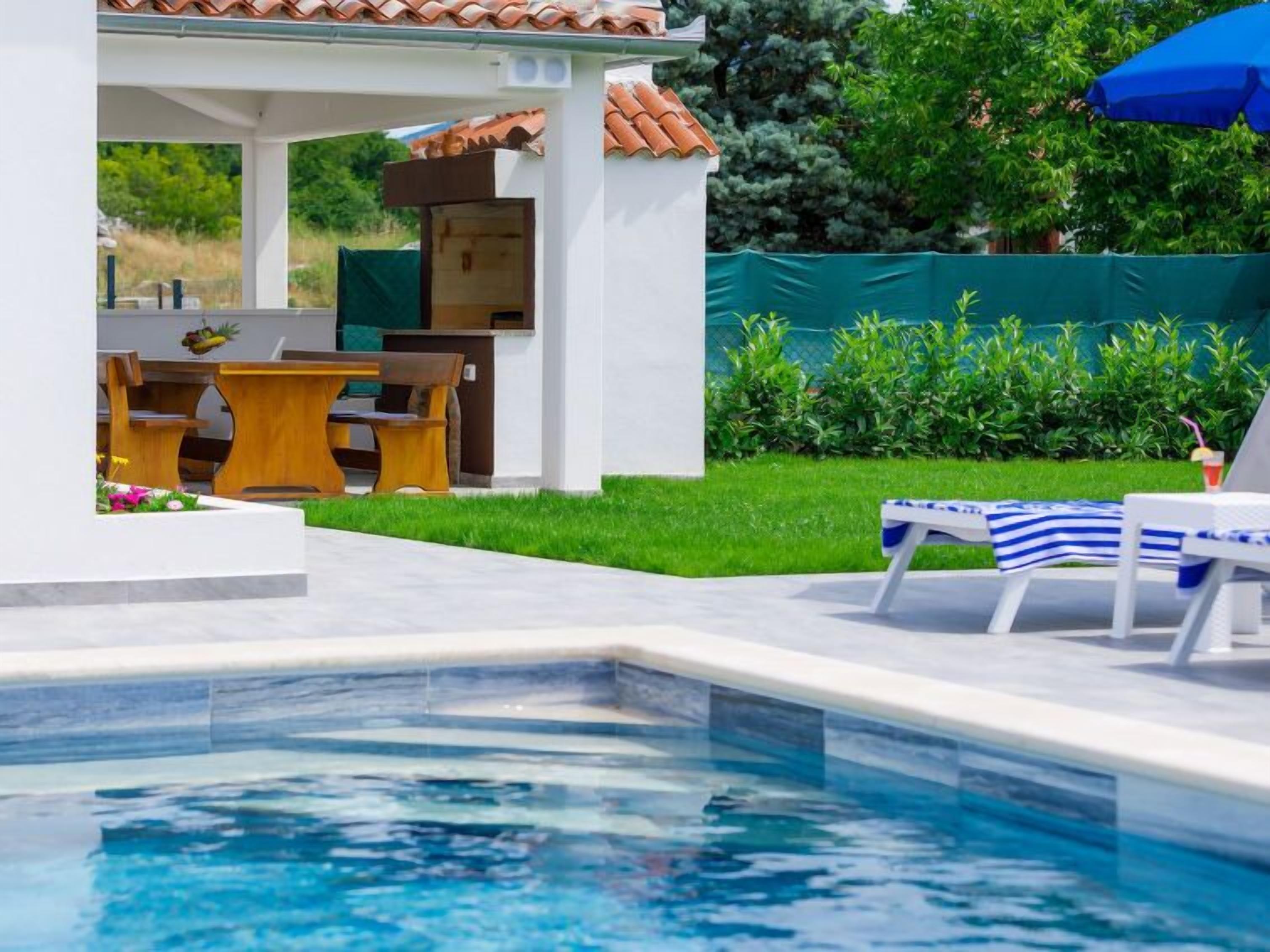 Piscina com espreguiçadeiras e um espaço de estar ao ar livre com mobiliário.