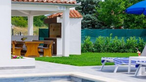 Une piscine avec des chaises longues et un espace patio aménagé avec du mobilier d’extérieur.