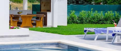 A swimming pool with lounge chairs and a patio area with outdoor furniture.