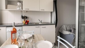 Een moderne keuken met witte kasten, een eettafel voor vier personen en een balkon met een barbecue.