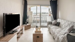 Een moderne woonkamer met een flatscreen televisie, een bank, een salontafel en een balkon met uitzicht.