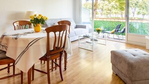 Una sala de estar moderna con comedor, ventanas grandes y vista a zonas verdes.