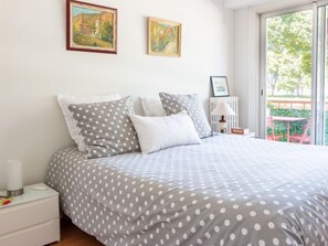 A bedroom with a bed, pillows, a nightstand, a lamp, and two paintings on the wall.
