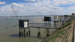 Un muelle de pesca frente al mar, con varias cabañas de pesca y un embarcadero que se adentra en el agua.