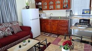 A compact living space with a kitchenette, a sofa, a dining table, and a red couch. - Cozy, comfortable, and beautiful apartment located in a safe gated community. (Georgetown)