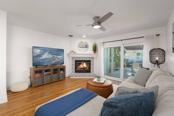 A modern living room with a fireplace, a television, and a balcony with a view.