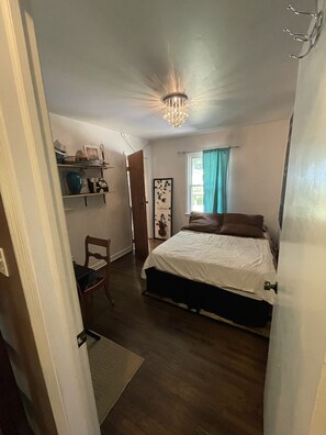 Relax in this serene bedroom with a large bed, chandelier, and comfortable chair.