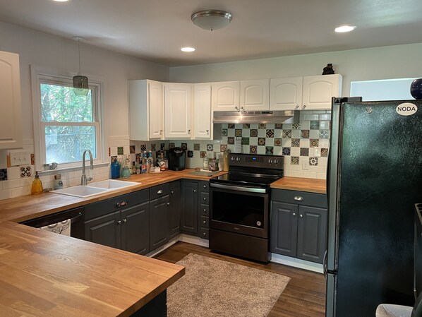 Enjoy cooking in this well-lit kitchen with a refrigerator, range hood, and ample cabinetry.