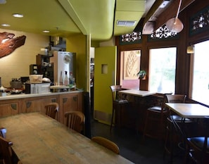 A kitchen with wooden cabinets, a refrigerator, and a dining area with a wooden table and chairs.