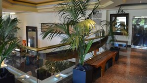 Un hall d’entrée moderne avec une rambarde en verre, un banc en bois et plusieurs plantes en pot.