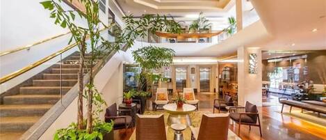 Eine großzügige Lobby mit einer zentralen Sitzecke, einer Treppe und mehreren Ebenen.