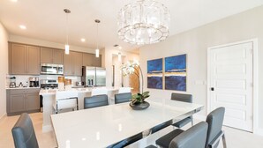 A modern kitchen with stainless steel appliances, a large island with seating, and contemporary decor. - 3BR Reunion Townhome w/ Golf Views & Games (Kissimmee)