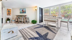 Um quarto amplo com uma janela grande, um banco de madeira, uma mesa e um tapete.