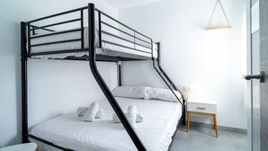 Un lit superposé avec une literie et des serviettes blanches, une table de chevet avec une lampe et un luminaire suspendu.