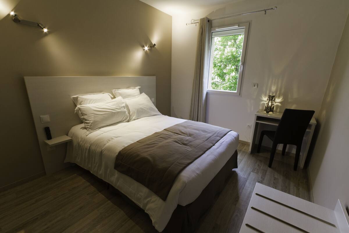 Un dormitorio con cama, mesita de noche y escritorio con silla.