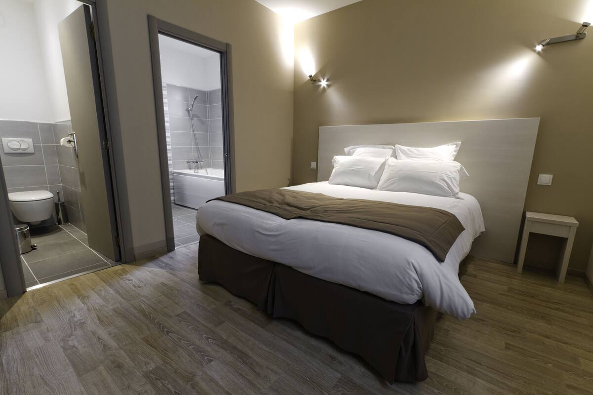 Un dormitorio moderno con una cama grande, una mesita de noche y vistas al baño.