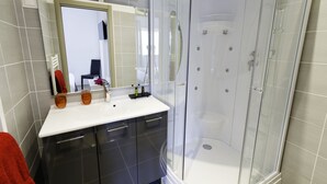 A modern bathroom with a glass-enclosed shower, a white sink, and dark cabinetry. - Hôtel Les Petits Oreillers (Saint-Martin-d'Ardèche)