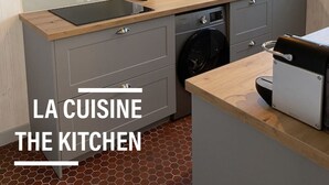 Eine moderne Küche mit grauen Schränken, einer Holzausziehtafel, einem Geschirrspüler und einer Spüle.