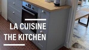 Eine moderne Küche mit grauen Schränken, einer Holz Arbeitsplatte und einem eingebauten Backofen.