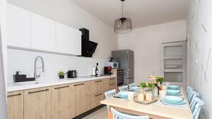 Una cocina moderna con armarios de madera, encimera blanca y comedor con mesa preparada para cuatro.
