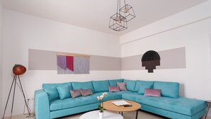 Una sala moderna con un sofá seccional color turquesa, una mesa de centro blanca y una lámpara de pie.