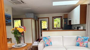 Una sala de estar moderna con un sofá blanco, almohadas coloridas, una mesa de centro de madera y un jarrón con flores.