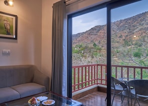 Relax on the balcony with a view of the surrounding mountains, featuring a round table and two chairs.