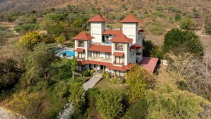 A large, multi-story building with a symmetrical design, featuring multiple towers and a swimming pool. - The Hunting Lodge (Udaipur)