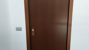 Una porta de fusta tancada amb una mànec de bronze i un ull de claus.