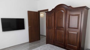 Un dormitori amb un llit, un armari i un televisor de pantalla plana fixat a la paret.