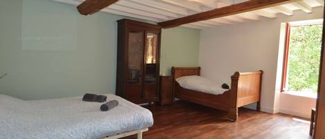 Un dormitorio con dos camas de madera, un armario y una ventana con vistas a zonas verdes.