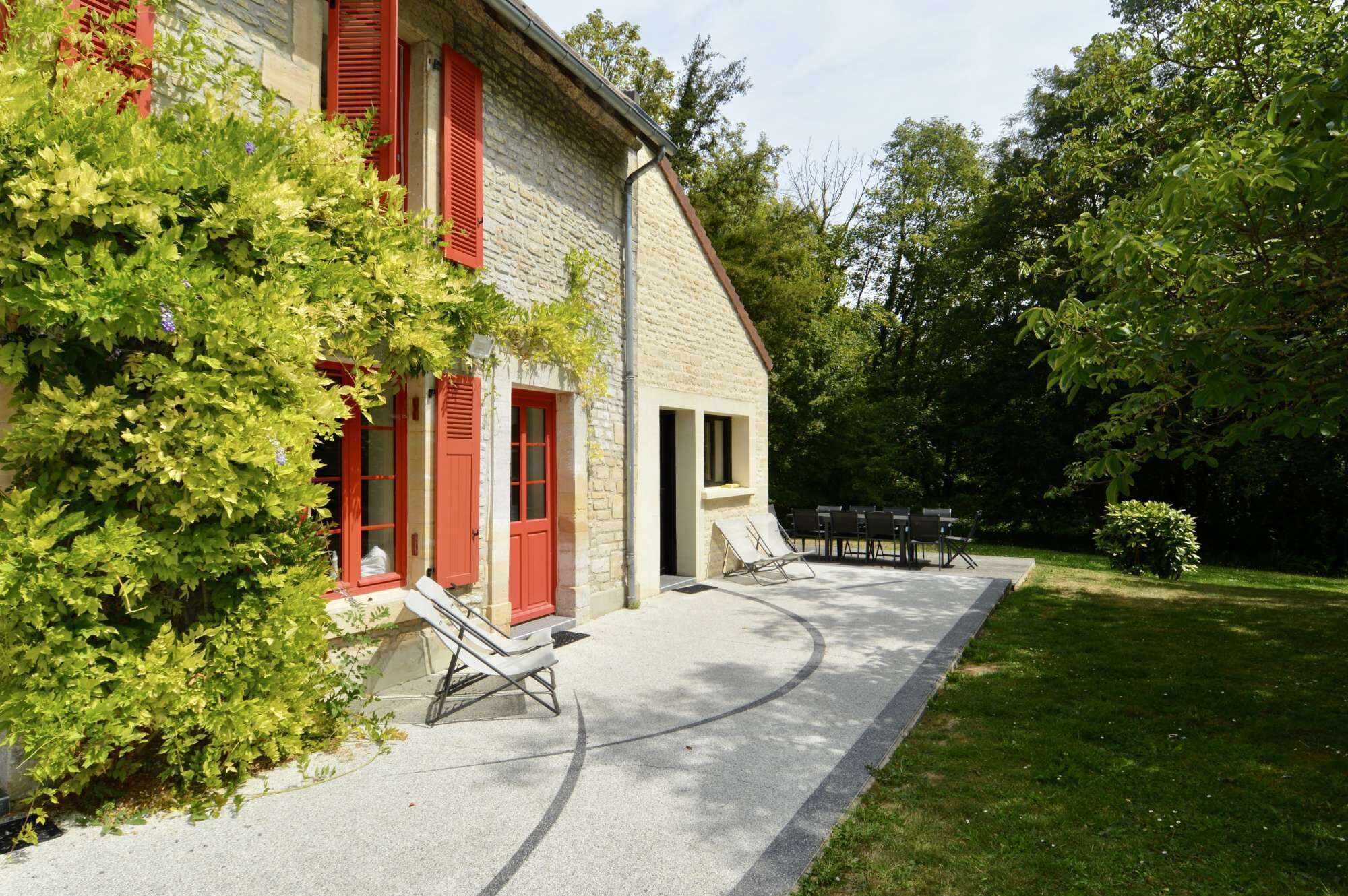 A house with a paved patio, a lounge chair, and a table with chairs.