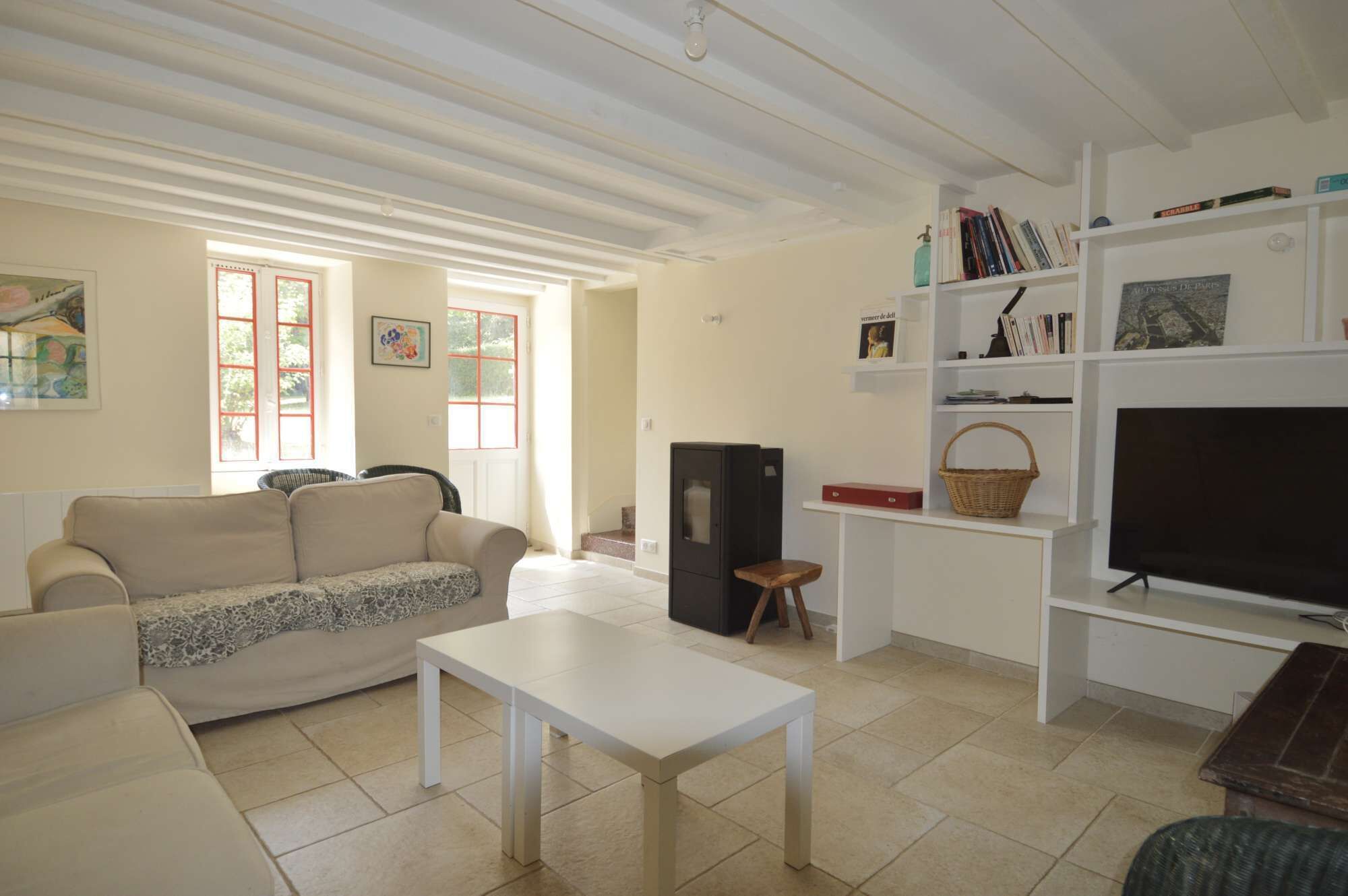A living room with a sofa, a coffee table, a television, a bookshelf, and a fireplace.