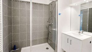 Une salle de bain moderne avec une douche à parois de verre, un lavabo blanc et un miroir.