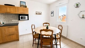 Une cuisine moderne avec des meubles en bois, un four à micro-ondes encastré et un coin repas comprenant une table ronde et des chaises.