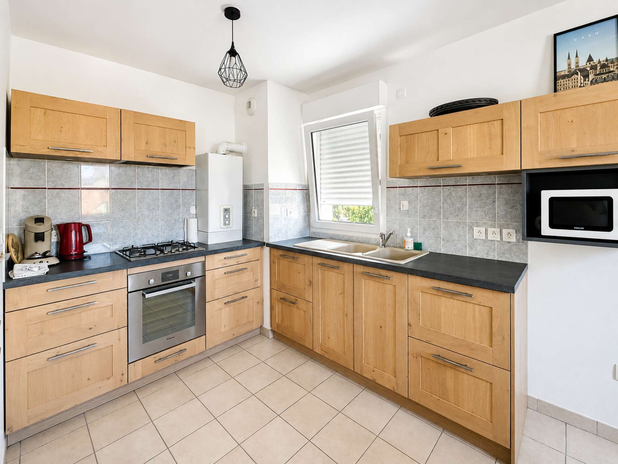 Una cocina moderna con armarios de madera, estufa a gas, horno, microondas y una ventana con persianas.