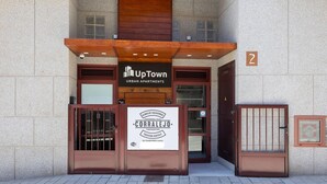 Ein Hauseingang eines Wohnhauses in der Stadt mit einem Schild für 'UpTown Urban Apartments' und einem Schild für 'CORRALEJO Vacation Rentals'.